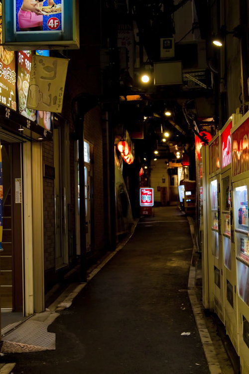 自動販売機と看板が灯る飲み屋の路地裏の夜