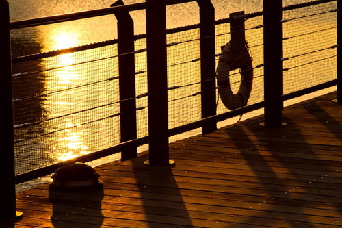 救命浮き輪がかかるデッキ越しの夕暮れの海