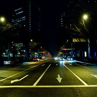 街灯とビルが並ぶ三車線の大通りの夜景の写真