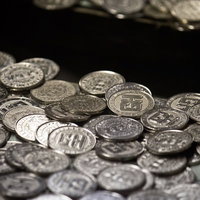 散らばった銀色のメダルが並ぶゲームセンターのメダル落としの写真