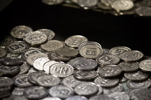 散らばった銀色のメダルが並ぶゲームセンターのメダル落とし