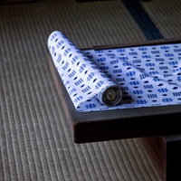 畳の上の木製トレーに広げられた和柄の生地の写真
