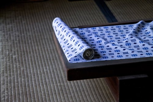 畳の上の木製トレーに広げられた和柄の生地