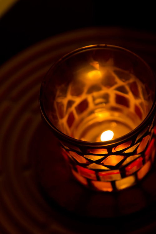 暗い室内で炎が灯るステンドグラスのろうそくホルダー