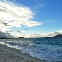 波が寄せる砂浜と遠くの島が見えるカイルアビーチの写真