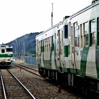 駅のホームですれ違う緑と白の烏山線の電車の写真