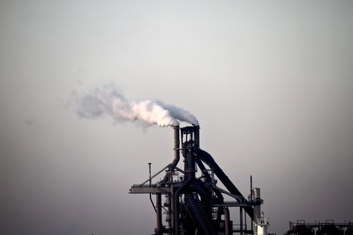 曇り空の下で煙を吐く工場の煙突と設備