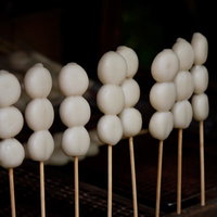 木の台に並ぶ白い串焼き団子の写真