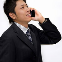携帯電話を耳に当てて話し中のサラリーマンの写真