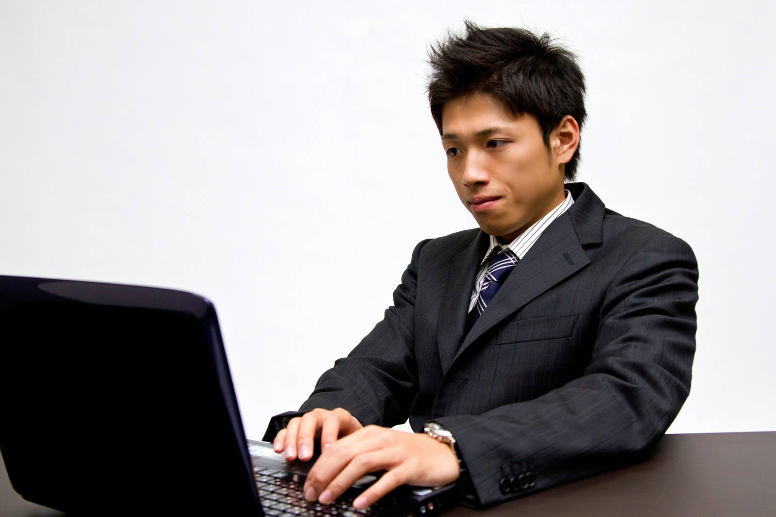 ノートPCで作業するスーツの男性［モデル：恭平］