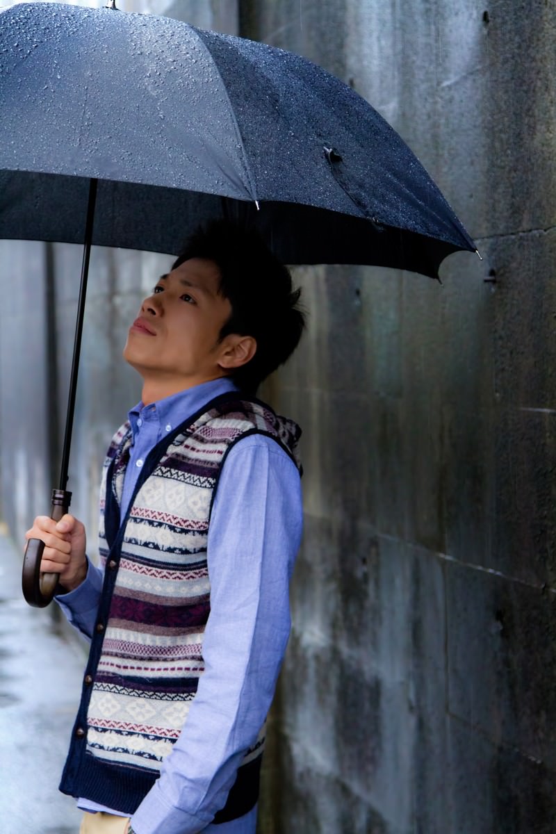 雨の日に紺色の傘を差す青年［モデル：恭平］