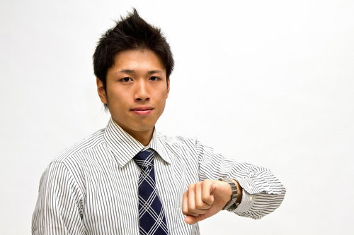 腕時計を確認するネクタイ姿のビジネスマン