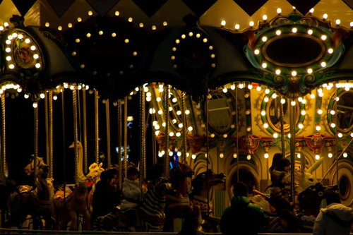 暗い夜空に色とりどりの電球で照らされたメリーゴーランド