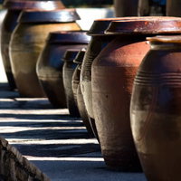 横線模様が入った茶色い陶器の壺が並ぶ屋外の写真