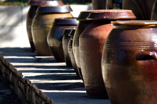 横線模様が入った茶色い陶器の壺が並ぶ屋外