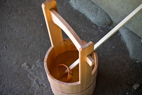 灰色のコンクリート地面に置かれた木製の桶と柄杓