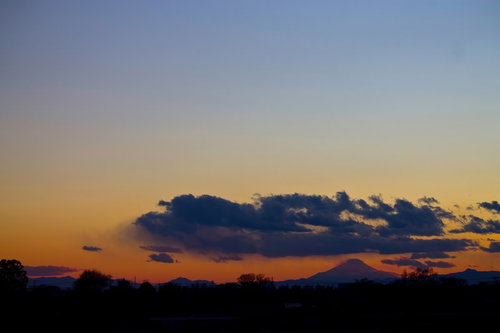 夕焼けの雲の向こうに浮かぶ富士山のシルエット