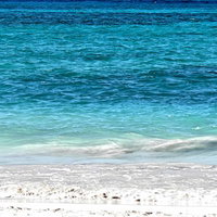 白い泡が砂浜に広がるラニカイビーチの透明な海の写真