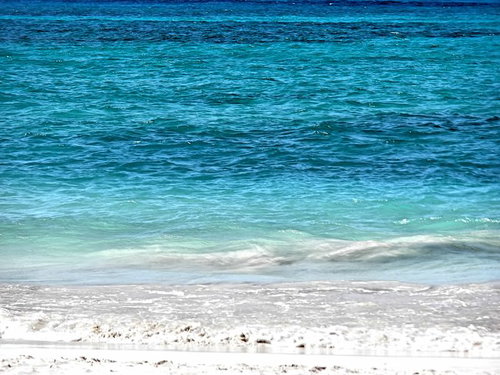 白い泡が砂浜に広がるラニカイビーチの透明な海