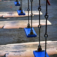 誰もいない公園に並ぶ青いブランコの写真