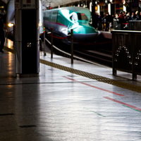 ホームに停車する緑色の新幹線と黄色い点字ブロックの写真