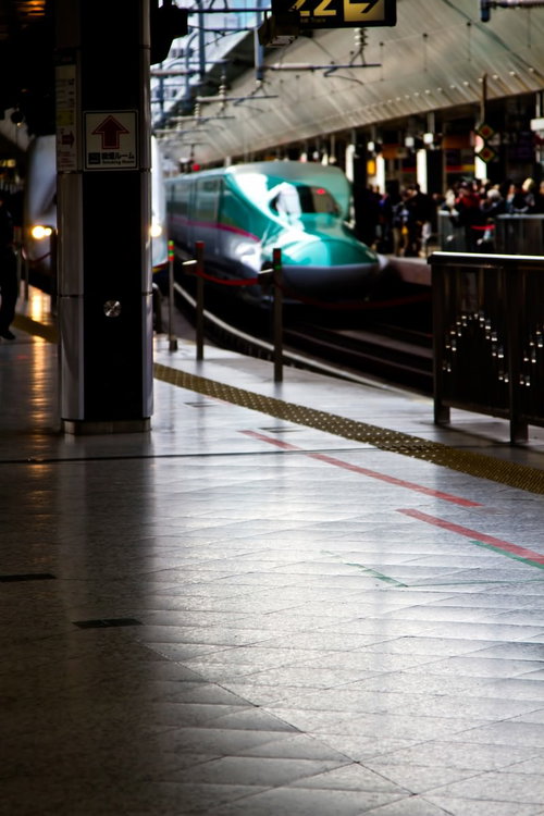 ホームに停車する緑色の新幹線と黄色い点字ブロック