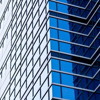 青いガラス窓が並ぶ空を反射する大きなビルの写真