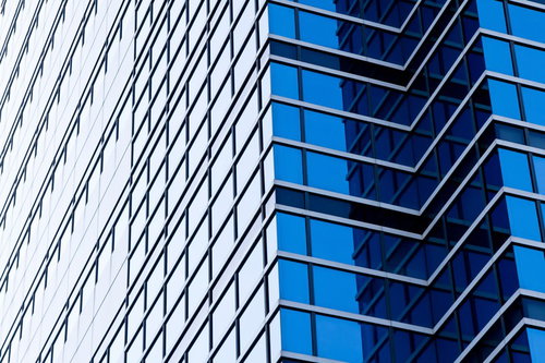 青いガラス窓が並ぶ空を反射する大きなビル