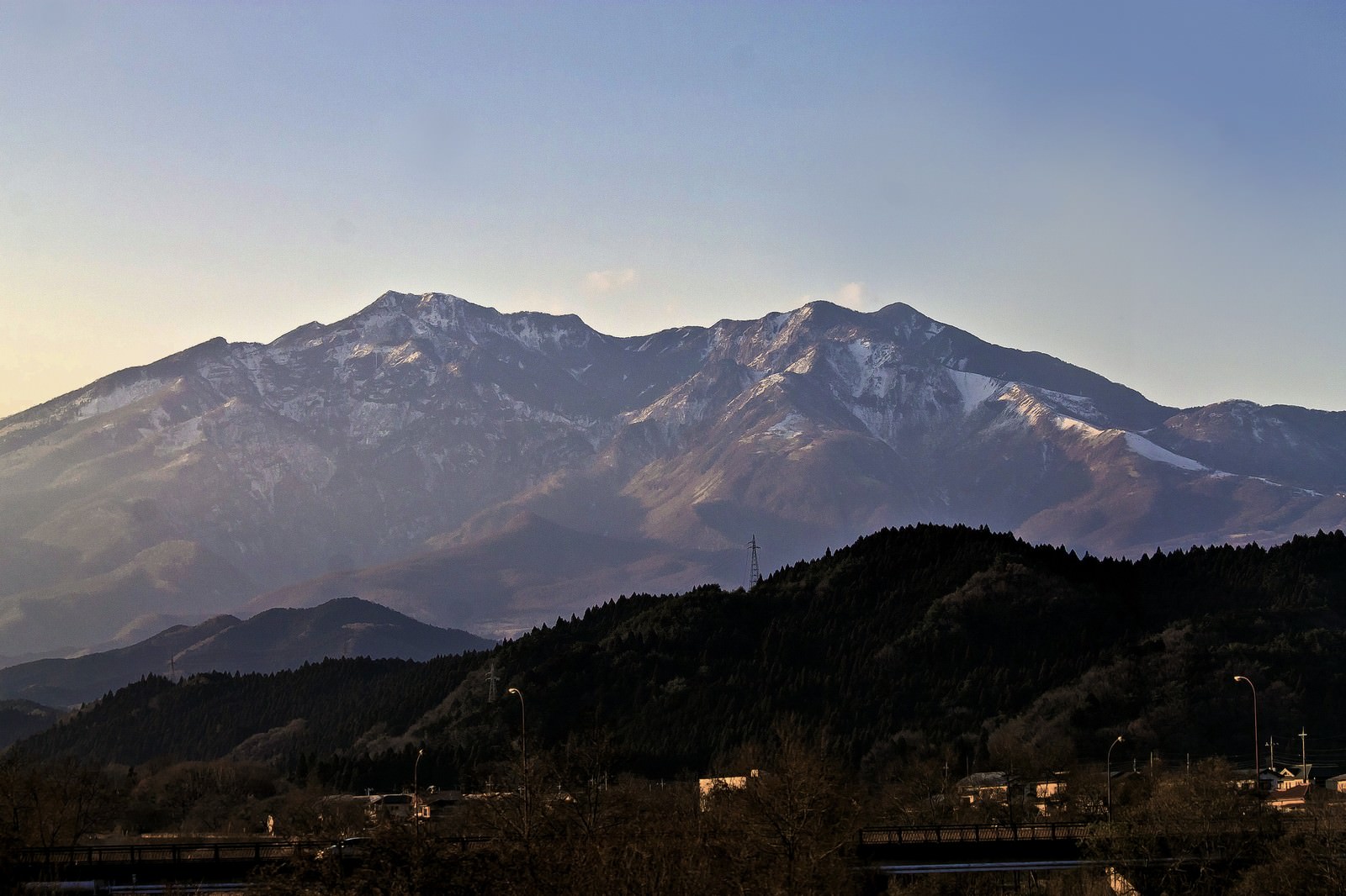 夕方の空に浮かぶ雪の残る山