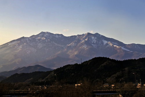 夕方の空に浮かぶ雪が残る山々と住宅地
