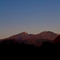 青からオレンジに変わる夕暮れ時の雪が残る山々の写真