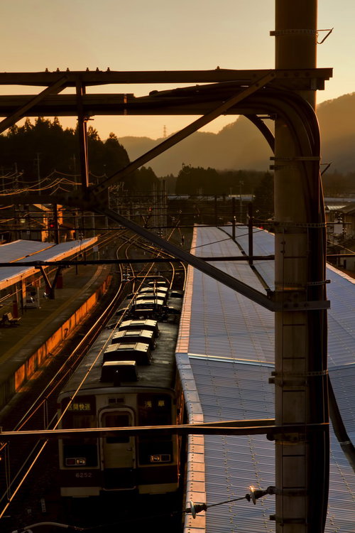 鉄骨の屋根越しに見える夕暮れのホームと電車