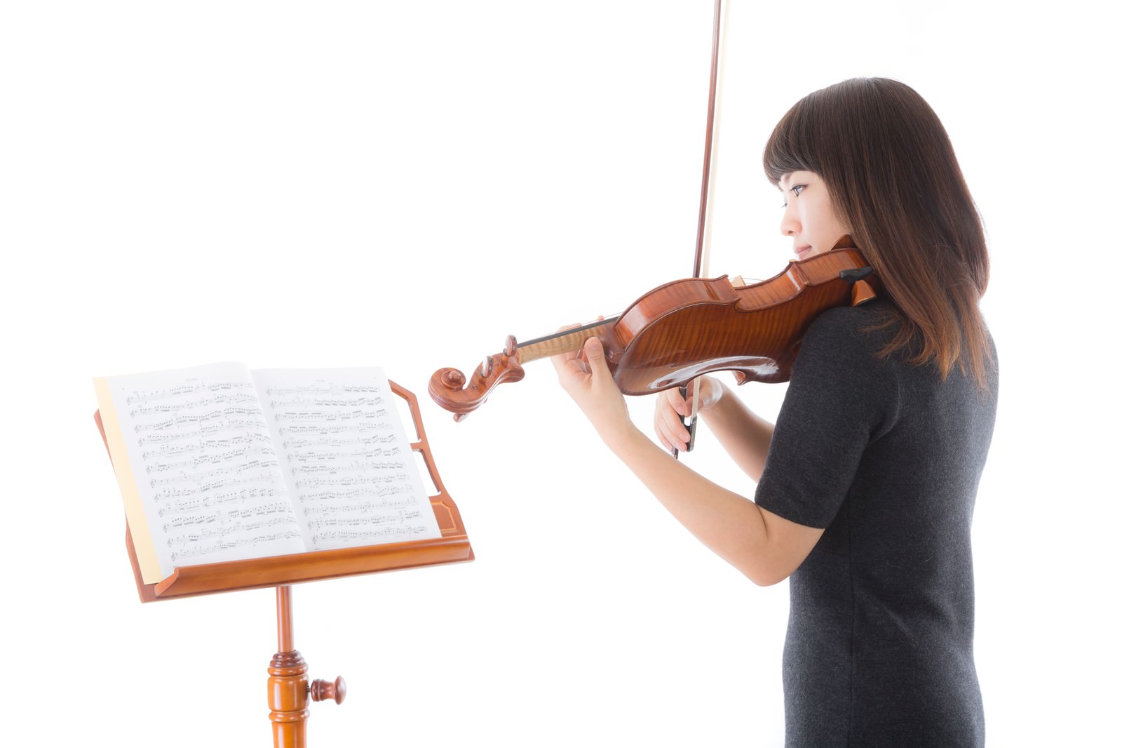 譜面を見ながらヴァイオリンを演奏する女性［モデル：yukiko］