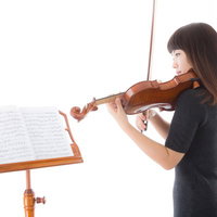 譜面を見ながら新しい曲を譜読みするヴァイオリニスト女性の写真