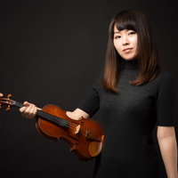 ヴァイオリンを片手に正面を見つめる女性の演奏家ポートレートの写真