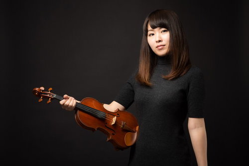 ヴァイオリンを片手に正面を見つめる女性の演奏家ポートレート