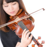 光の中でヴァイオリンを演奏する女性の肖像の写真