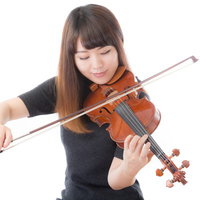 優雅にヴァイオリンを弾く黒いトップスの女性の写真