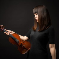 ヴァイオリンを見つめる女性演奏家の真摯な表情の写真