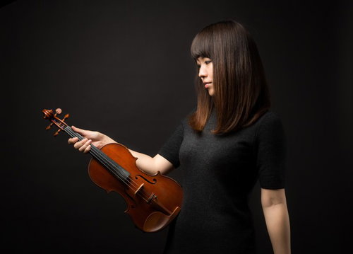 ヴァイオリンを見つめる女性演奏家の真摯な表情