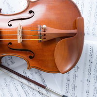 楽譜の上に置かれたヴァイオリンと弓の楽器の写真