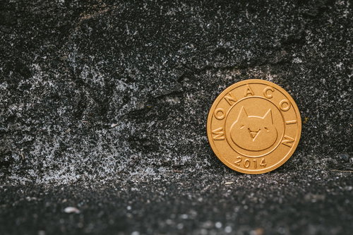 ヒビ割れた壁に置かれたモナコインの金色コイン