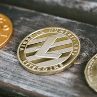 木製テーブルに並ぶライトコインと暗号資産コインの写真