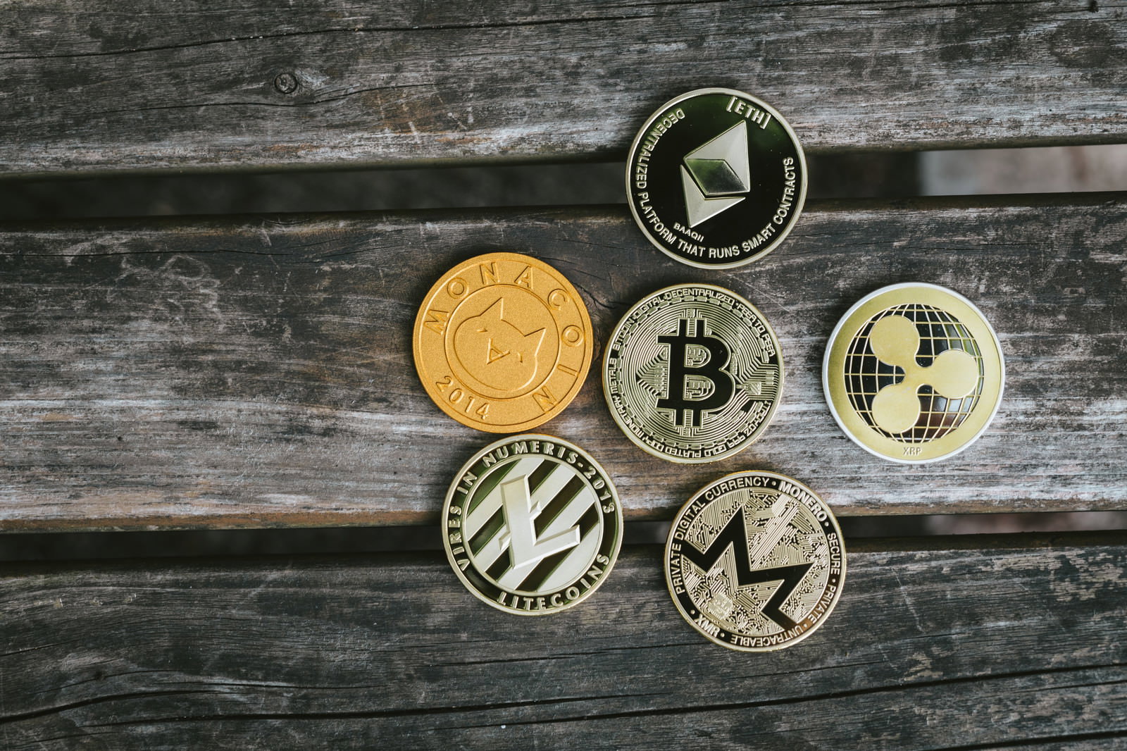 古い木製テーブルの上に金色と銀色の仮想通貨コインが複数並べられている