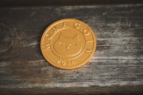 木目背景に置かれた金色のモナコイン
