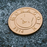 オマエモナコイン、石の上に置かれた銅色のコインの写真