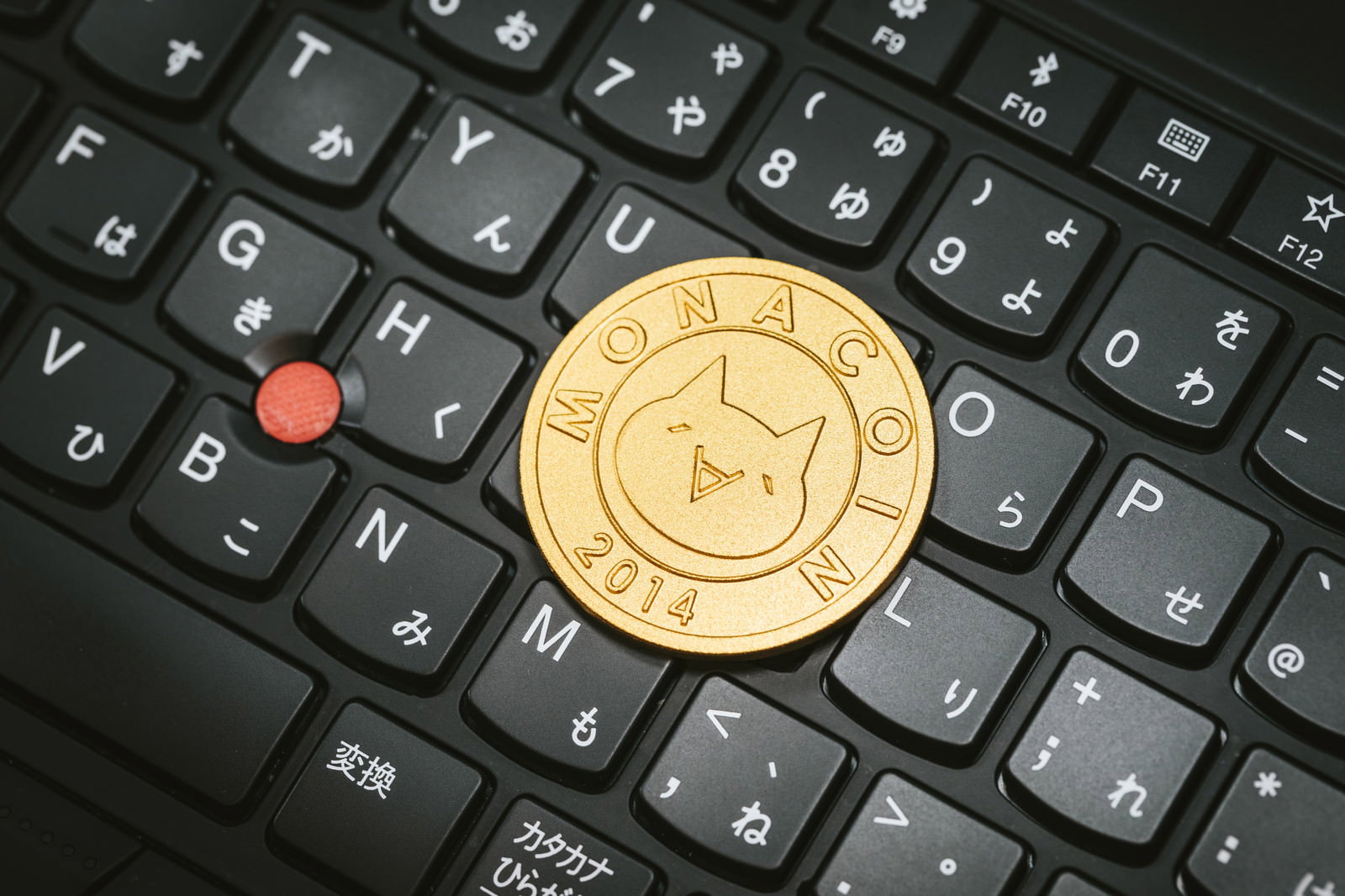 黒いキーボードの上に置かれた金色のモナコイン