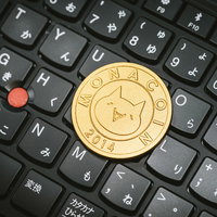 黒いキーボード上に置かれた金色のモナコインの写真
