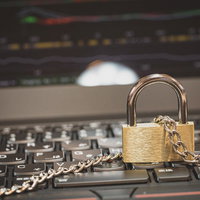 パソコンのキーボードと鎖に繋がれた南京錠の写真