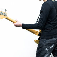 暗いステージでベースギターを構えるベーシストの後ろ姿の写真